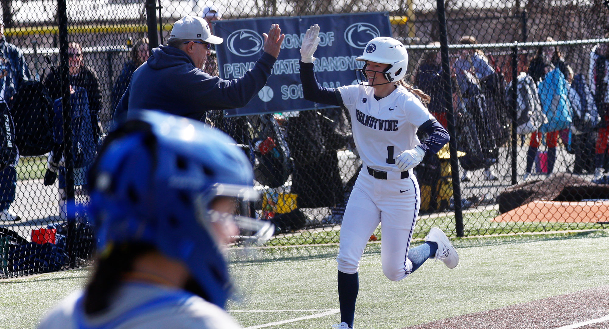 softball player high-fives coach