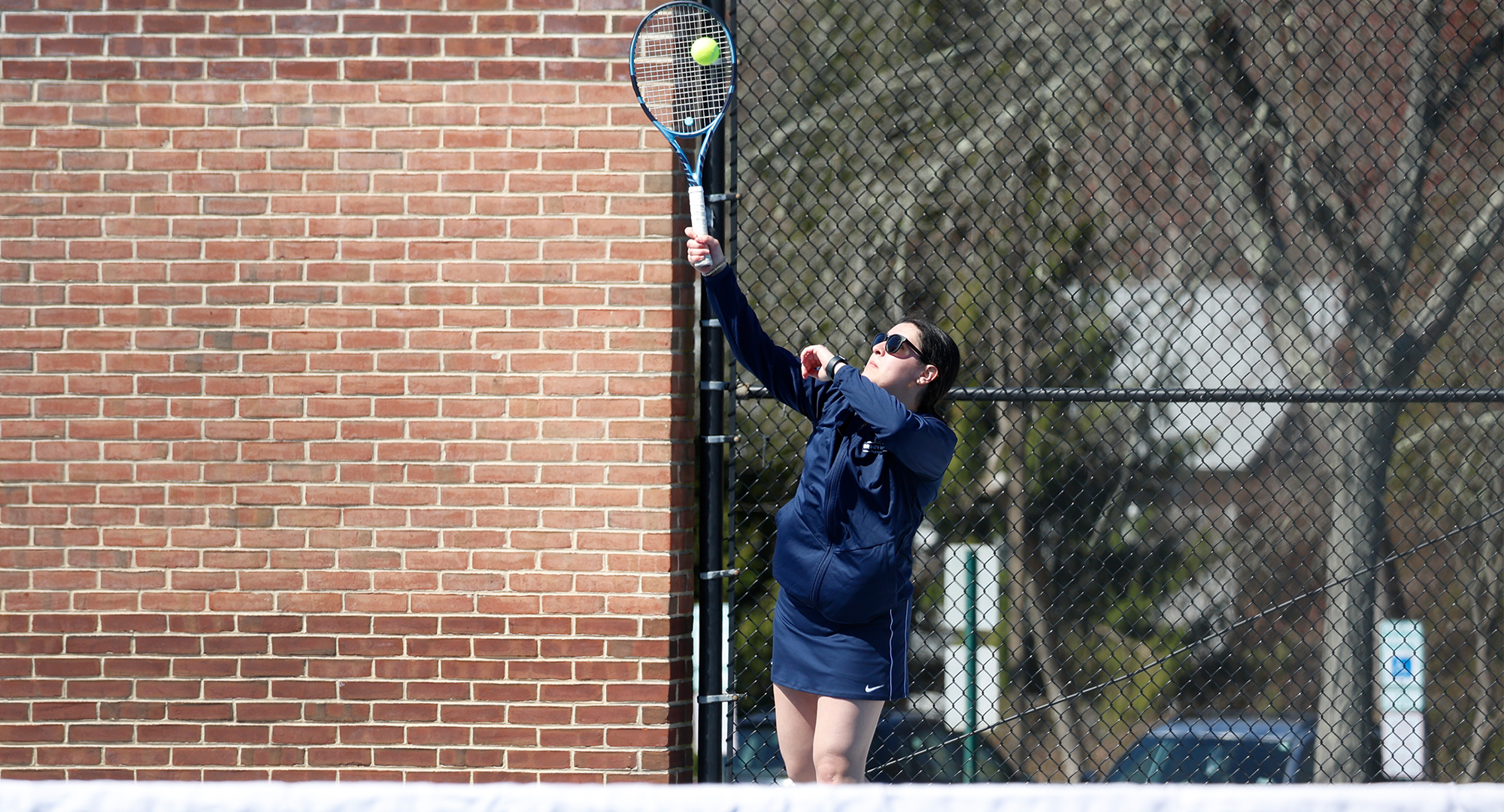 women's tennis player serves a ball