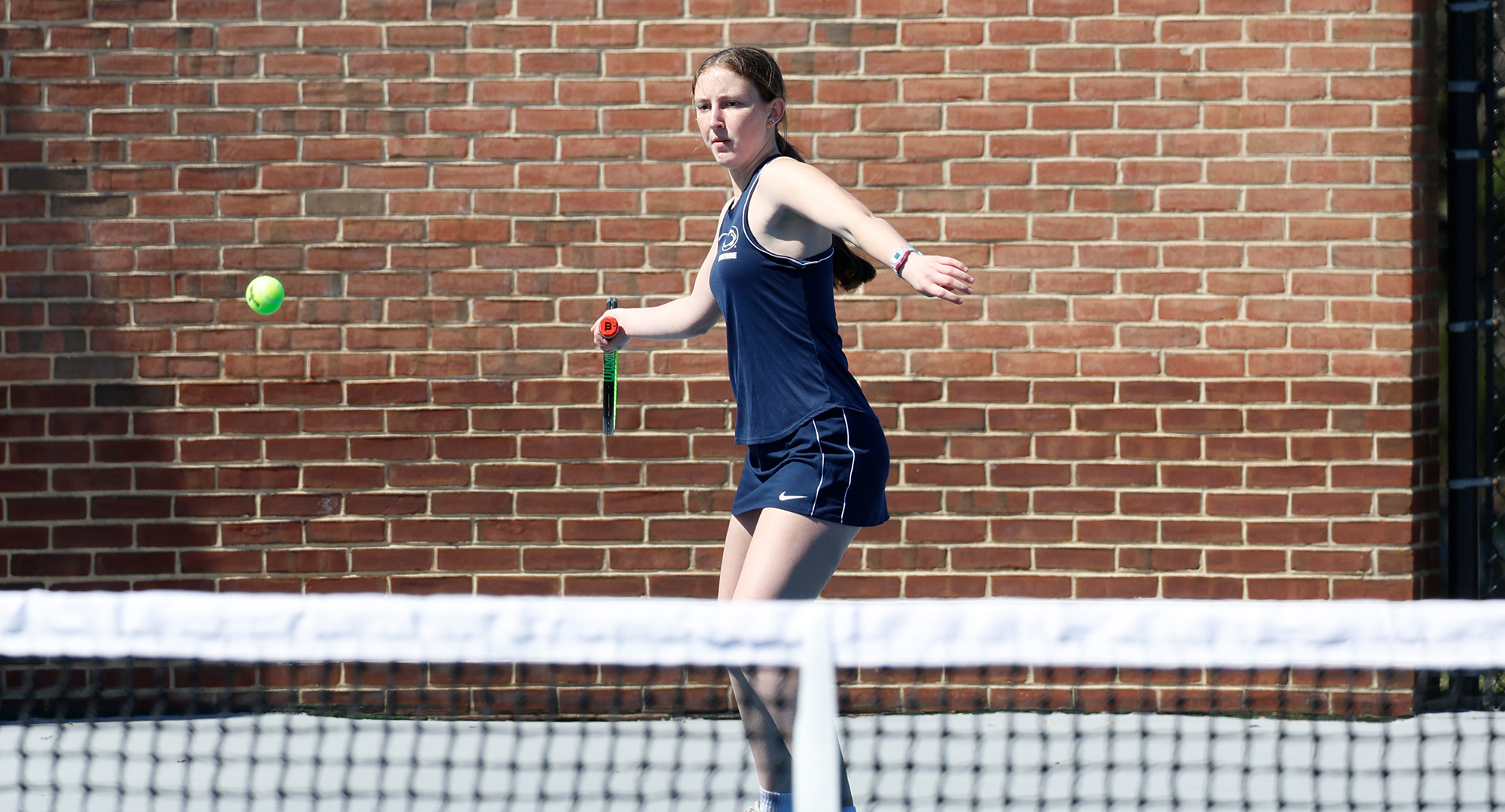 women's tennis player winds up to hit ball